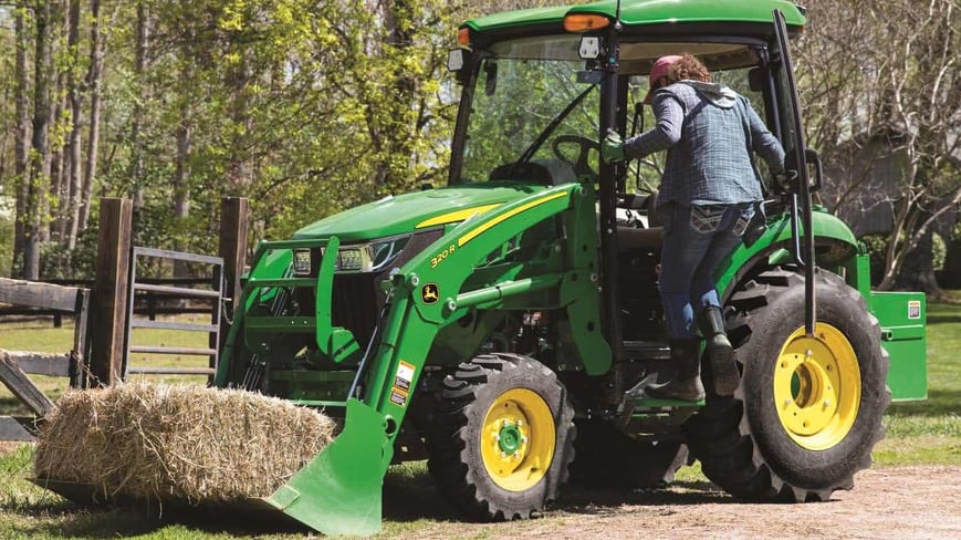 Woman getting into a compact utility tractor cab