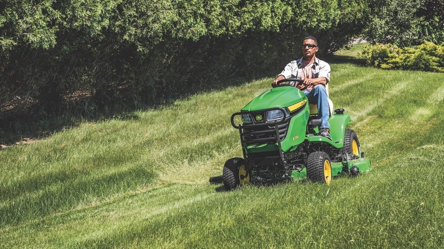 man on x350 series lawn mower mowing on a hill