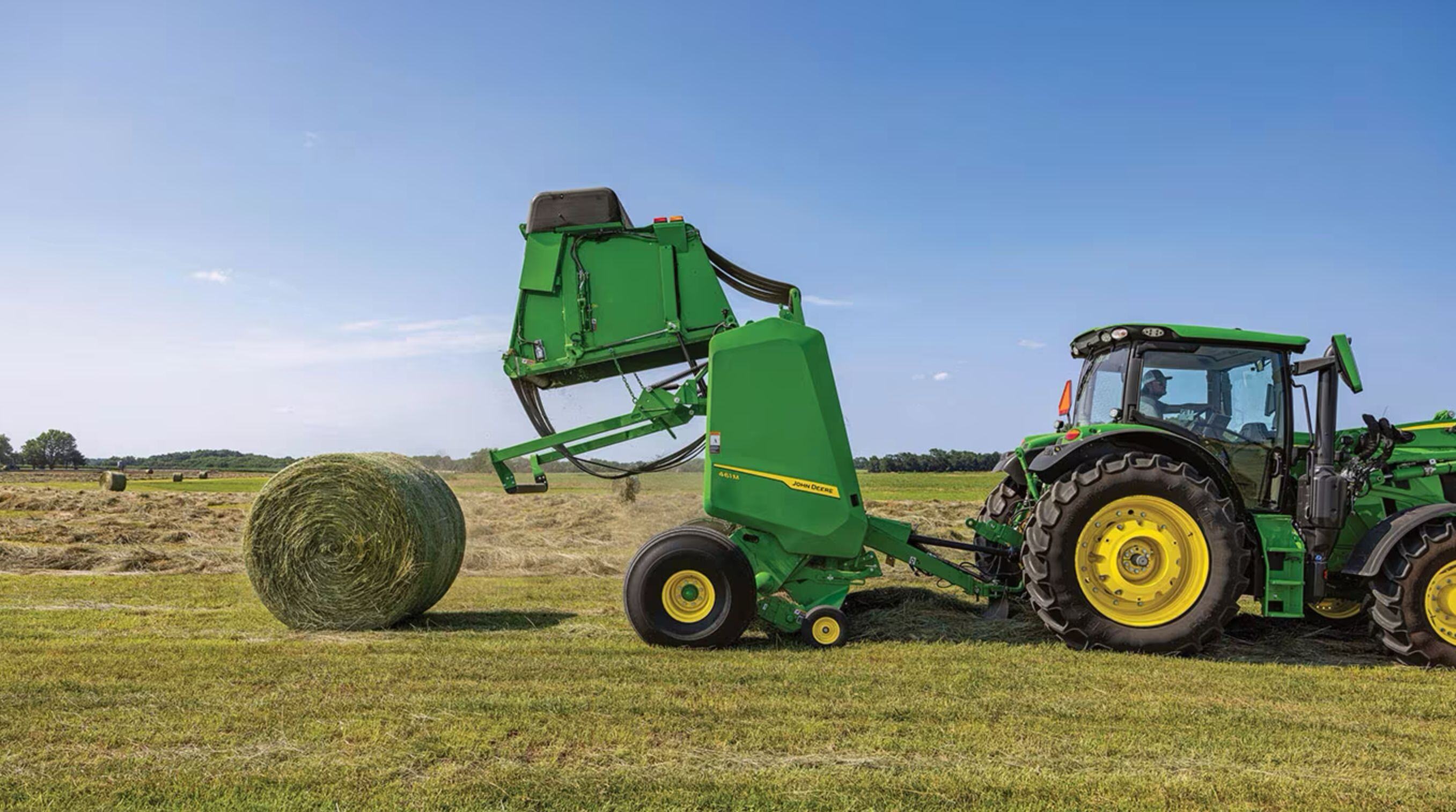 John Deere 461M round baler depositing a bale in the field — Koenig Equipment