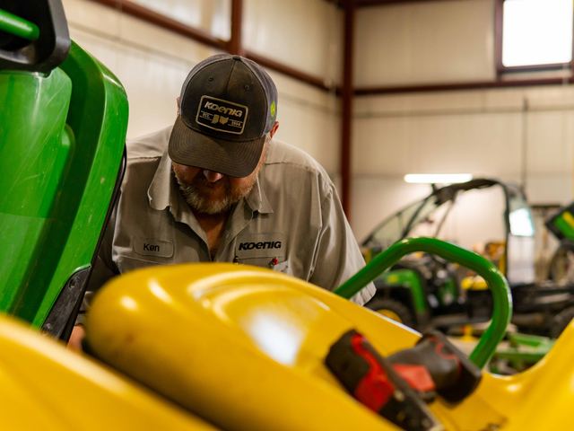 A Koenig Equipment technician working on a John Deere machine in the service shop