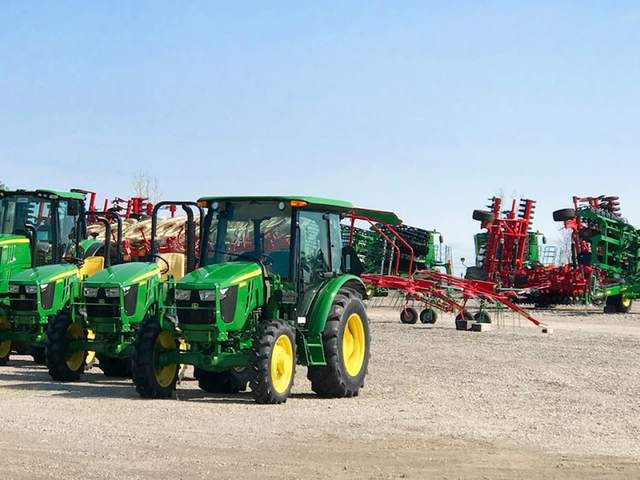 John Deere tractors and farm implements lined up on a Koenig Equipment lot